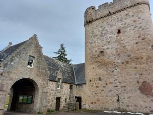 un gran edificio de piedra con una gran torre en Courtyard Cottage - Drum Castle en Banchory