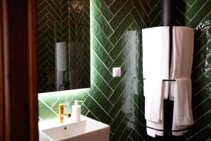 a green bathroom with a sink and a mirror at Ti Noémia - casa de vila in Minde