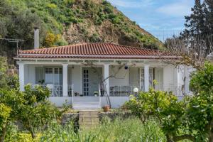 uma casa branca com uma colina ao fundo em Heliotropio em Kalamaki