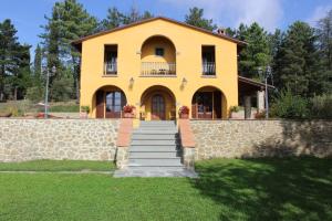 a yellow house with stairs in front of it at Villa Rondinocco in Civitella in Val di Chiana