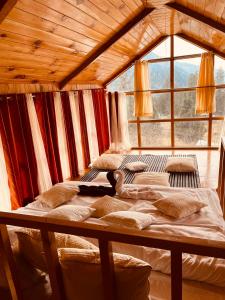 a bedroom with two beds and a large window at The Villster Resort in Kasol
