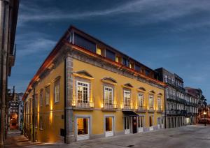 a yellow building with white windows on a street at Pousada do Porto - Rua das Flores in Porto