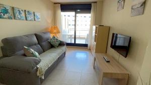 uma sala de estar com um sofá e uma televisão em Sueños del Mar 1 By Alquileres El Conserje em Denia