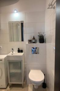 a white bathroom with a toilet and a sink at Apartament Abrahama 40 in Gdynia
