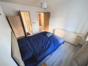 1 dormitorio con 1 cama azul y suelo de madera en Spacious 2 Bed Flat, Free Parking, Close to town, en Mánchester