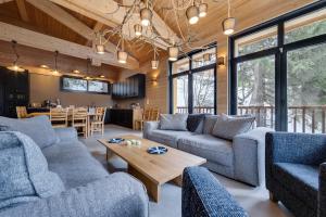 salon z niebieskimi kanapami i stołem w obiekcie Chalet du Bois Melay - piscine - proche pistes - 15 personnes w mieście Plagne 1800