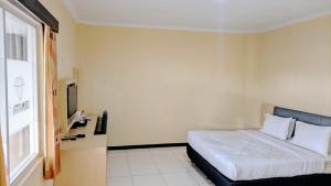 a hotel room with a bed and a window at Permata Inn Slawi in Procot