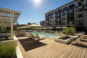 a pool with chairs and umbrellas next to a building at Mountain View 1br w wd pool gym nr tech HQs SFO-1183 in Sunnyvale