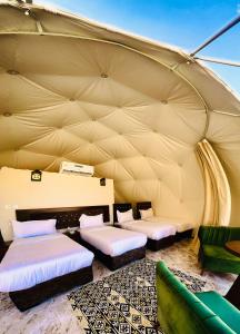 um quarto com três camas numa tenda em Darien Luxury Camp em Wadi Rum