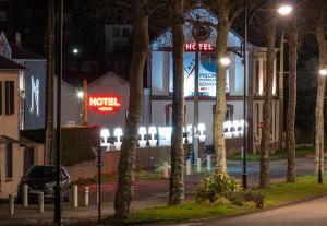 una strada di notte con un cartello e alberi dell'hotel di LE M HOTEL & SPA HONFLEUR a Honfleur