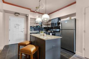 a kitchen with a stainless steel refrigerator and stools at Designer Corner Suite 3br/2ba - Disney, Universal, Convention Center & SeaWorld in Orlando