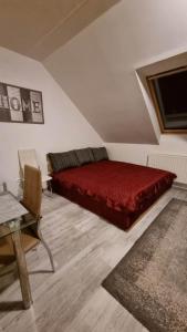 a bedroom with a red bed and a table at Csodaszép in Békéscsaba