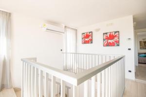 Una escalera blanca en una habitación con dos cuadros en la pared en La Casa sui Giardini, en Vieste