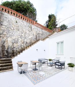 un patio con mesas y sillas junto a una pared de piedra en LAA Studios, en Coímbra