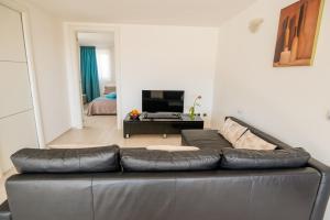 un sofá de cuero negro en una sala de estar con TV en La Casa sui Giardini, en Vieste