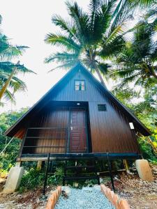 a small house with a palm tree in front of it at WildStag Dandeli in Dandeli