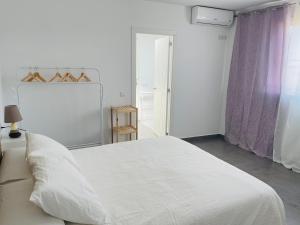 a white bedroom with a large white bed and a window at Duplex ático Bajo de Guía in Sanlúcar de Barrameda