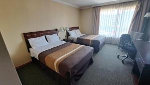 a hotel room with two beds and a desk at Hotel Diego de Almagro Temuco in Temuco