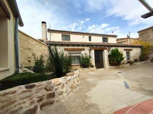 a house with a stone wall and a driveway at El Cortijo del Piron in Losana de Pirón