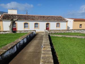 a white building with red doors and a grass yard at Riviera Beach B in Praia da Vitória