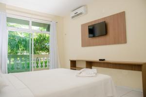 a bedroom with a bed and a tv and a window at Hotel Acarau Riviera in Acaraú