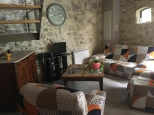 una sala de estar con sofás y un reloj en la pared en Petite maison sur jardin secret, en Aviñón