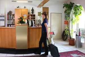 Hotel Harsshof في زالتسغيتر: امرأة تقف في مكتب الاستقبال مع أمتعتها