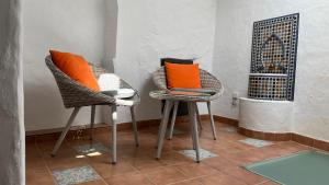 2 Stühle mit orangefarbenen Kissen in einem Zimmer in der Unterkunft Casa Casco Historico in Frigiliana
