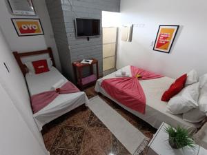 two beds in a small room with a tv at Pousada Torre dos Mouros in Pirenópolis