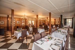 a dining room with white tables and chairs in a restaurant at Graskop Hotel in Graskop