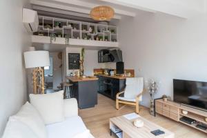 salon z białą kanapą i kuchnią w obiekcie Maison chaleureuse à 5 mins des remparts w mieście Aigues-Mortes