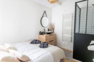 Schlafzimmer mit einem weißen Bett und einem Spiegel in der Unterkunft Maison chaleureuse à 5 mins des remparts in Aigues-Mortes
