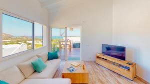 ein Wohnzimmer mit einem Sofa und einem TV in der Unterkunft SUNSEEKER SXM - Jardins Orient Bay - Appartement vue mer ou Studio vue Colline in Saint Martin