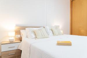 a bedroom with a large white bed with a book on it at Salinas Mar y Playa in Roquetas de Mar +70 photos