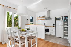 a white kitchen with a white table and chairs at Apartamento Can Harmonia - Arenal den Castell in Arenal d'en Castell