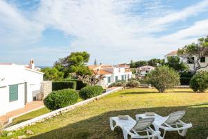 a view of the yard of a house with white chairs at Apartamento Can Harmonia - Arenal den Castell in Arenal d'en Castell