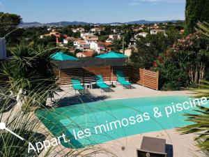 a swimming pool with chairs and a view of a city at Mimosas - villa in Fréjus