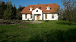 Biały dom z pomarańczowym dachem na dziedzińcu w obiekcie Dworek Cicha Noc w mieście Tarnowo Podgórne