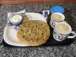 - un plateau avec une assiette de nourriture et deux tasses de café dans l'établissement Negi Lodge Chandigarh, à Chandigarh