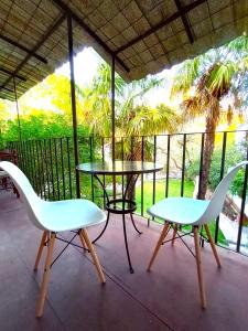 2 sillas blancas y una mesa en un porche en Aires de Coria en Chacras de Coria