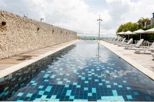 a swimming pool next to a stone wall with blue tiles at Yak Beach Hotel Natal in Natal