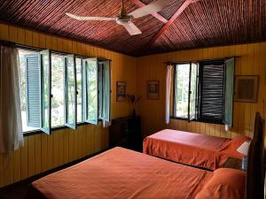 Duas camas num quarto com janelas e um tecto em Hotel Veragua River House em Sierpe