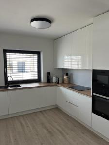a kitchen with white cabinets and a large window at Golf Villa Stella s bazénom in Šajdíkove Humence