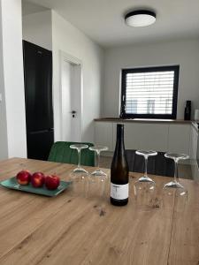 una botella de vino y algunas manzanas rojas en una mesa en Golf Villa Stella s bazénom, en Šajdíkove Humence