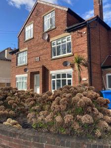 une maison en briques avec des fenêtres et des buissons devant elle dans l'établissement Park View Apartment, à Bridlington