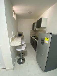 a small kitchen with a refrigerator and a stool at Cómodo apto 202 muy cerca a CC Unicentro Cúcuta in Cúcuta