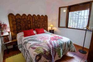 Un dormitorio con una cama con almohadas rojas. en La Balconera de Ana, en Puebla de Don Rodrigo