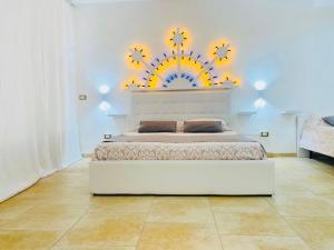 a bedroom with a white bed with a flower mural on the wall at Dimora al Mare in Villanova di Ostuni