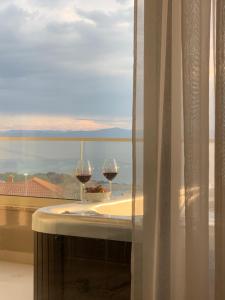 two glasses of wine sitting on a table in front of a window at Mali Raj Makarska in Makarska