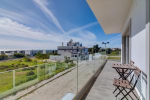 - un balcon avec deux bancs et une vue sur un bâtiment dans l'établissement FormosaFuzeta Seaview @Homesbyfc, à Fuzeta